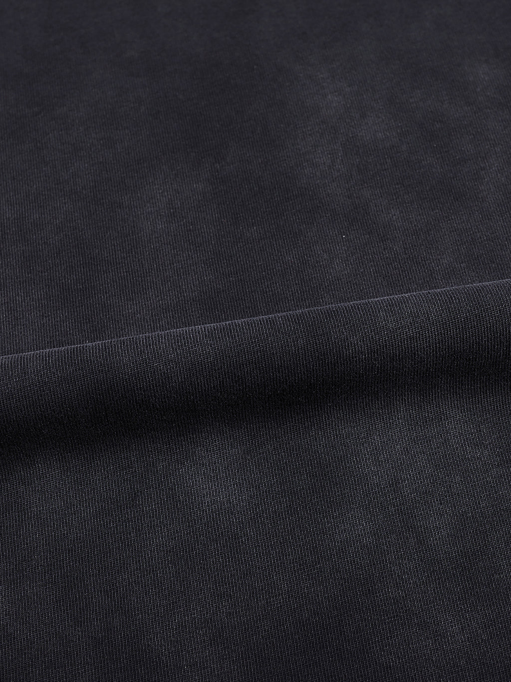 Macro detail of the vintage black-gray washed 100% cotton fabric used in the Meme Boutique tee